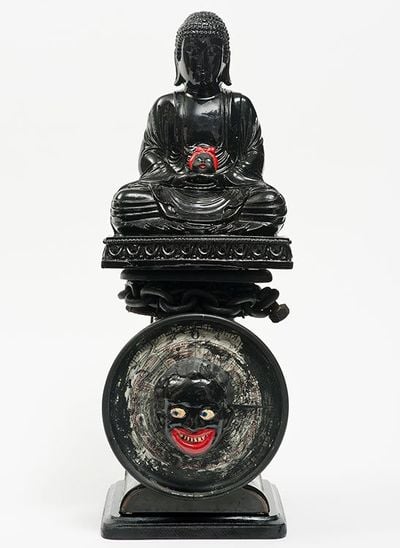Black painted Buddha figure holding child on postal scale