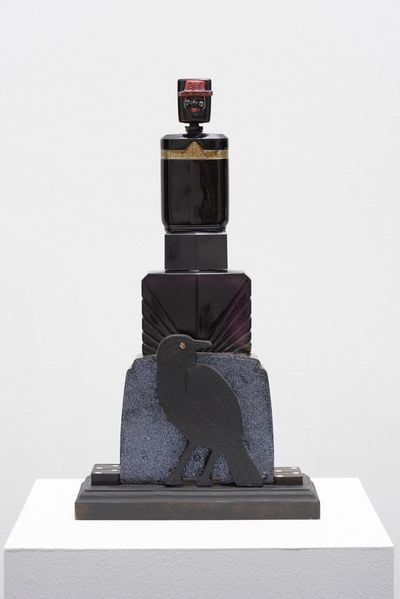 Grinning black face atop mix-media sculpture raven at the bottom