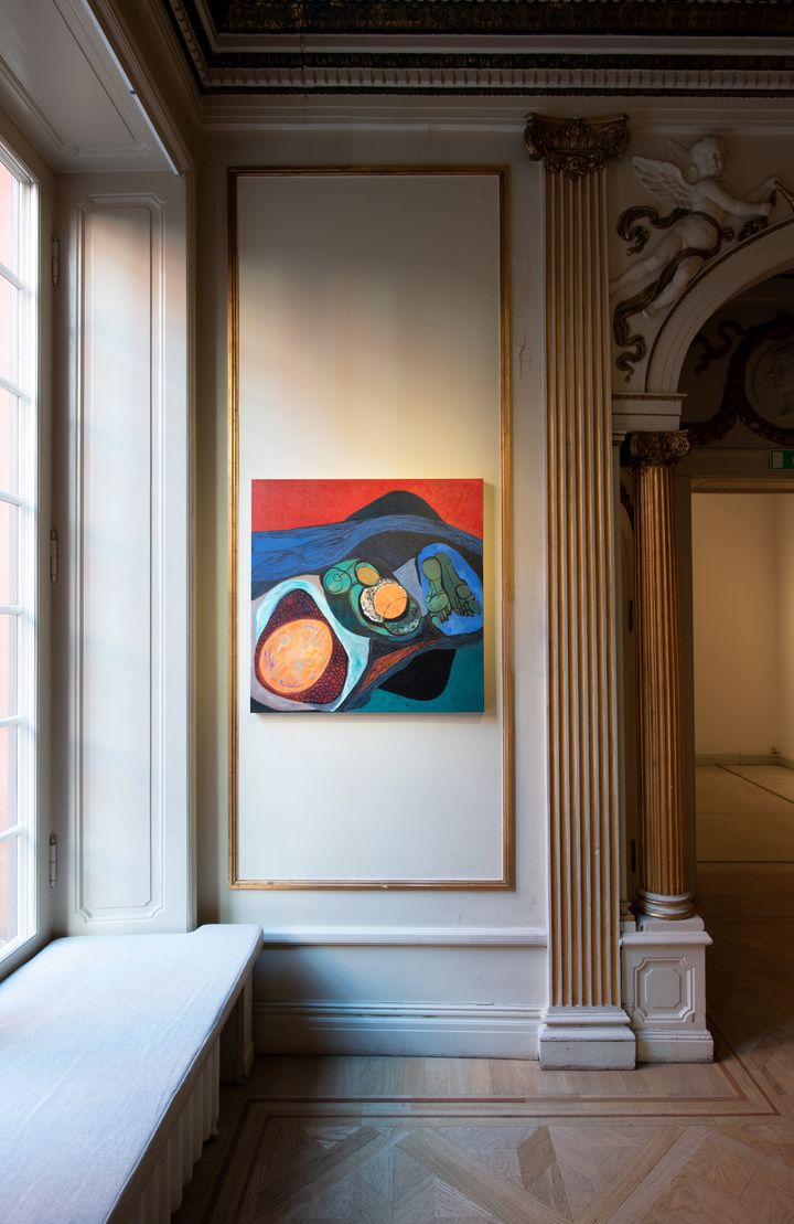An abstract painting hangs next to a window in the gallery class=