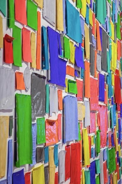 Rectangles of colourful paper are pinned to the wall and closely photographed, showing a sea of colour.