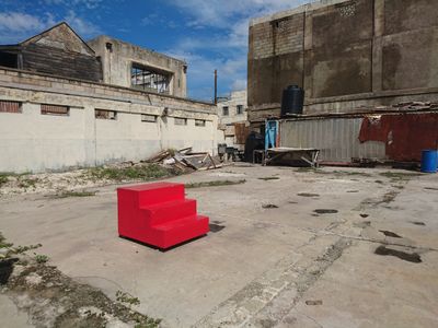 A set of three red stairs forming a block structure is placed in a barren environment.