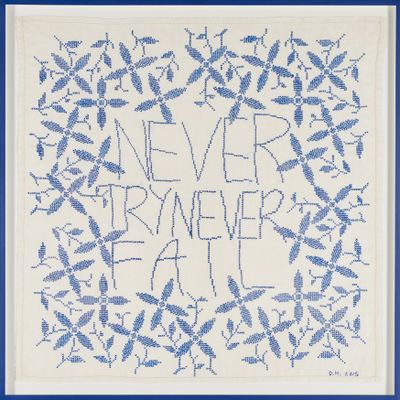 A square of embroidery featuring the words 'Never Try Never Fail' is surrounded by embroidered plant stems.