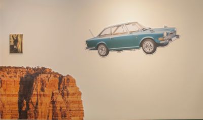 Exhibition view of Jang Jong Won and Glamour Shot showing a blue American chevy car flying off a canyon cliff with a small poster of a donkey floating on top of the canyon