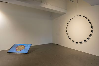 A video screen on the floor features the Shell logo, and is accompanied by a sculptural installation on the wall to the right that features a circle of asphalt shards.