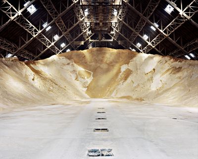 A photograph featuring a pile of sugar in an industrial warehouse space.