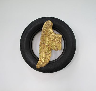 A sculpture by artist Paolo Canevari, entitled Angel (1998), of a golden wing sitting agains a black rubber tyre