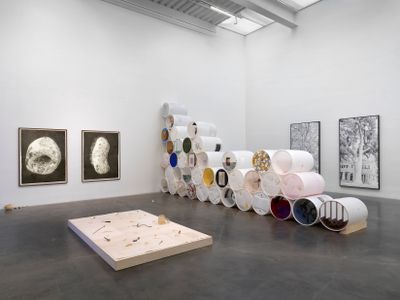 Floor installation, stacked sculptures, panel paintings, and monochrome prints in exhibition space