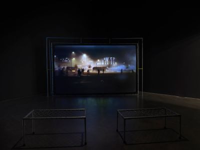 Film shown on large screen in front of two metal benches