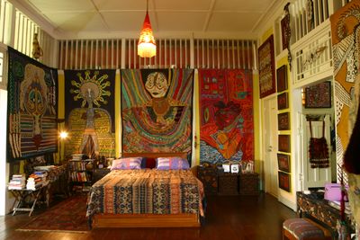Bedroom ornamented with African tapestry,  tribal patterns, and books.