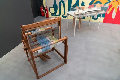 A weaving loom sits in the gallery space, photographed from above.
