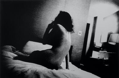 A photograph entitled Provoke 2 (1968/2018) by Daido Moriyama of a nude woman smoking in a hotel room