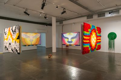 A series of four, horizontal vibrantly coloured works by Dalara Tukano hang in the exhibition, one featuring black, white, yellow, and orange zig zags, with two others featuring eagles.