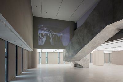 A video projection artwork by artist Xu Zhen, projected high near the ceiling against a concrete wall