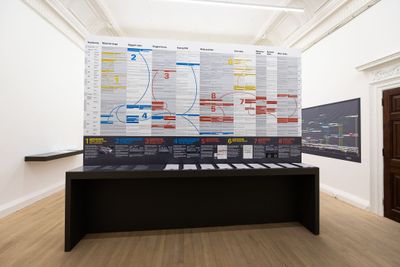 Installation shot of a large information desk showing articles & flyers of the exhibition of War Inna Babylon: The Community's Struggle for Truths and Rights.