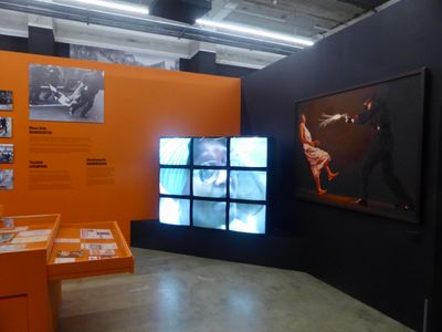 Installation shot of 9 video screens & wall text about the exhibition War Inna Babylon at Institute of Contemporary Art