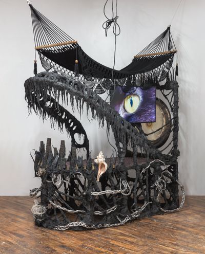 Guadalupe Maravilla, Disease Thrower #0 (2022). Gong, hammock, L.C.D. T.V., ceremonial ash, pyrite crystals, volcanic rock, steel, wood, cotton and glue mixture, plastic, loofah, objects collected from a ritual of retracing the artist's original migration route. 299.7 x 312.4 x 162.6 cm. © Guadalupe Maravilla.