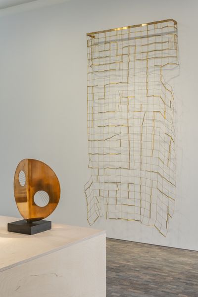 Left to right: Barbara Hepworth, Disc with string (Sun) (1969). Bronze and string on slate base. 53.7 cm height; Leonor Antunes, anni #26 (2020). Brass. 280 x 150 x 20 cm. Exhibition view: Creating Abstraction, Pace Gallery, London (3 February–12 March 2022).