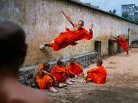 A young monk runs along the wall over his peers at theShaolin Monastery in Henan Province, China by Steve McCurry contemporary artwork print