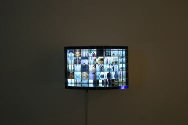 forty friends and family slowly approached the camera and looked into the camera. this image is shown on monitor with 40 segmented metal grids in front. The grid of metal disciples distorts and transforms people in the image