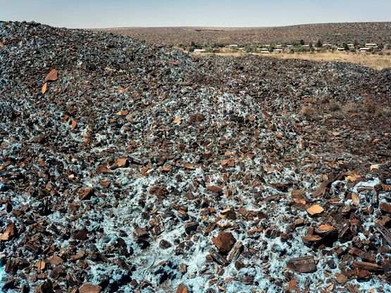 Highly carcinogenic blue asbestos waste on the Owendale Asbestos Mine tailings dump near Postmasburg Northern Cape. The prevailing wind was in the direction of the mine officals houses at right. 21 December 2002 by David Goldblatt contemporary artwork Print